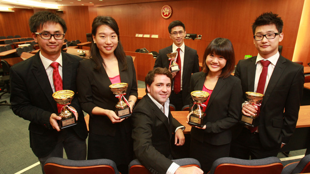 四名法律学院学生在教练Michael Ramsden教授（前坐）和麦铭贤（後站）带领下，在第七届亚洲国际模拟法庭比赛中勇夺冠军及最佳书面陈述奖。