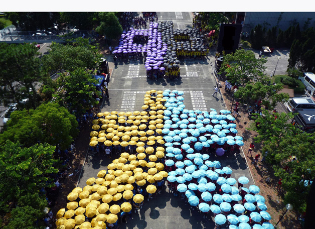 2009年入学的新生在迎新营展示创意。各书院的学生撑着不同颜色的雨伞，在百万大道砌出「中大」两个中文字。